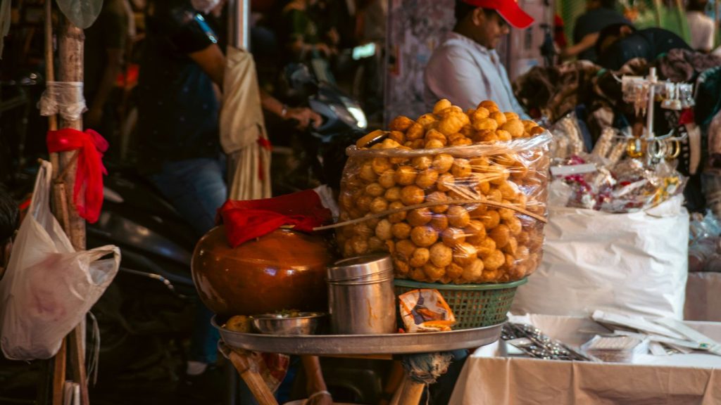 Street vendor selling snacks with large container of food.
