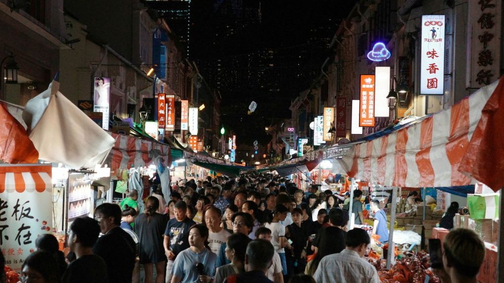 Crowded street market at night with stalls and signs